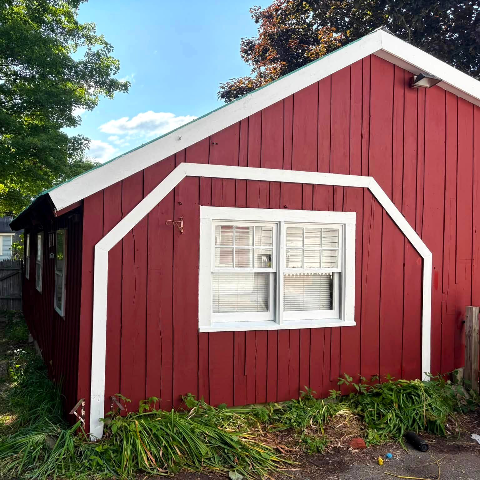 A freshly painted deep red barn with crisp white trim under a blue New Hampshire sky