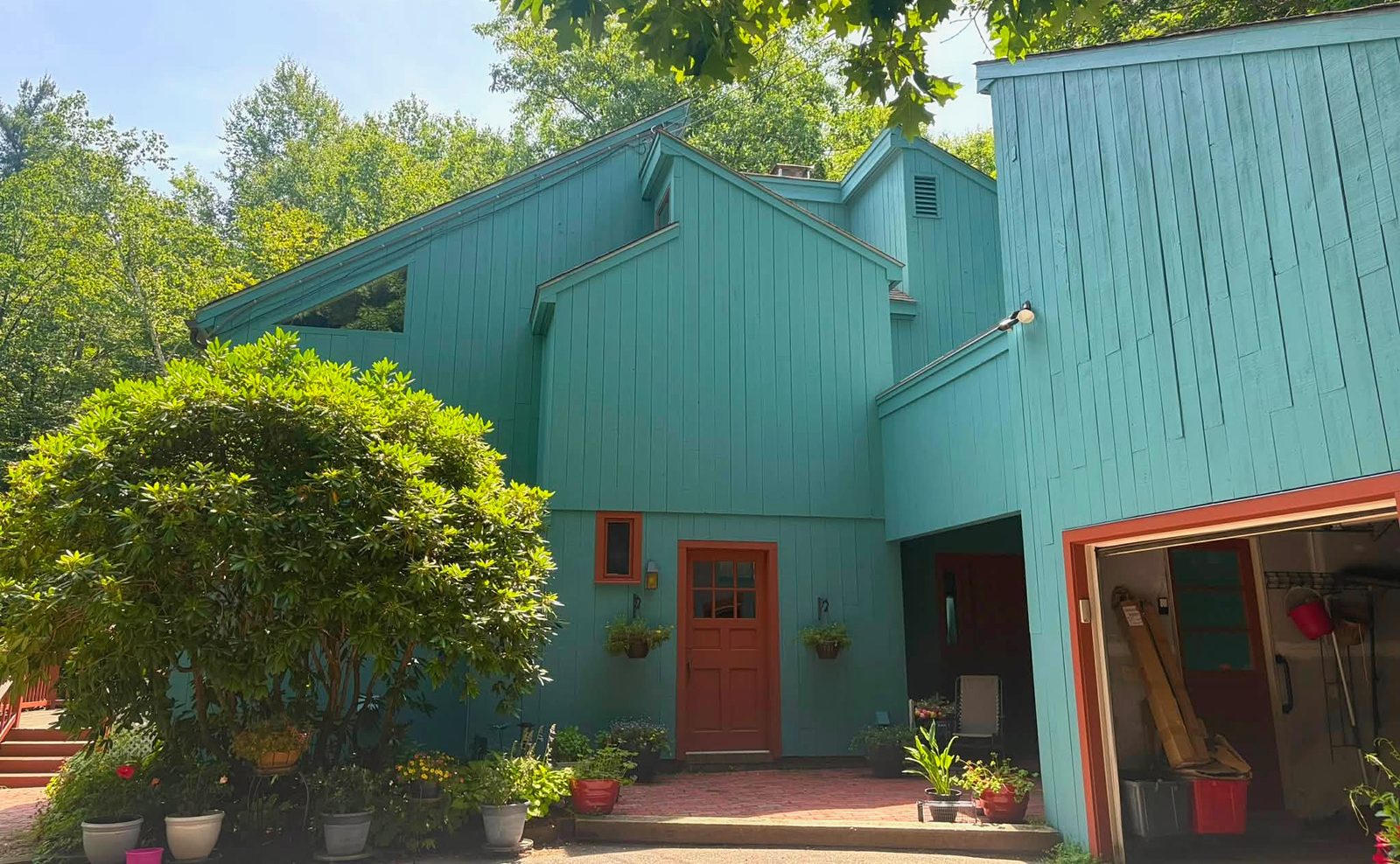 A teal-painted New England home with a red front door and fresh trim