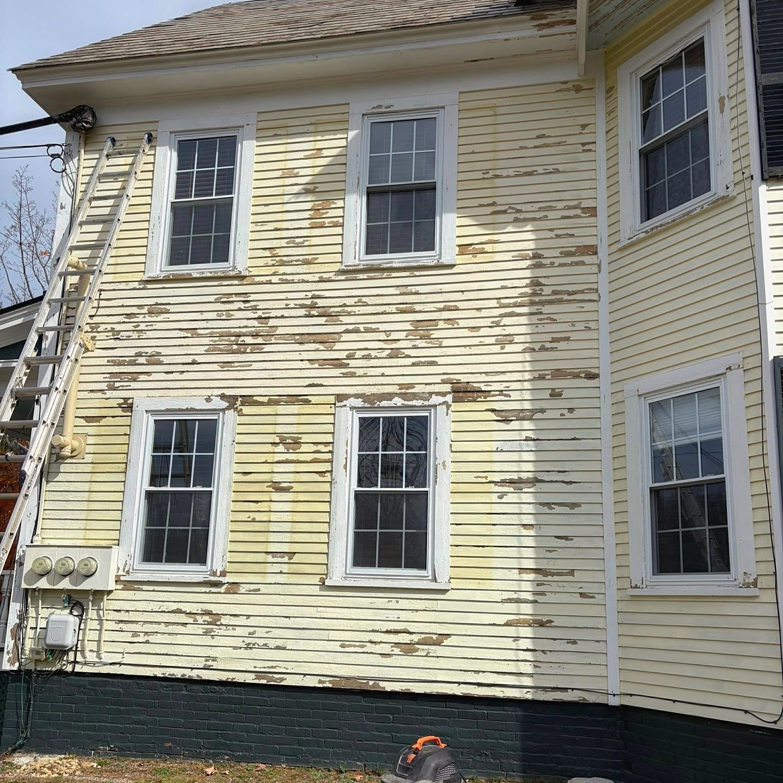 Before: peeling, chalked-out yellow clapboard on a three-story home